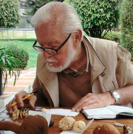 Gaston Guzman mycologist working at a table with wild found mushrooms.